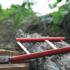 Folding camp saw resting on a log