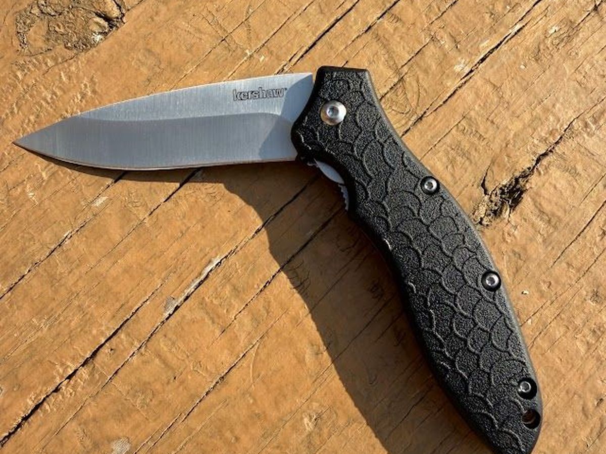Kershaw Oso Sweet open on a weathered wooden bench, showing the satin drop-point blade and scale-textured handle